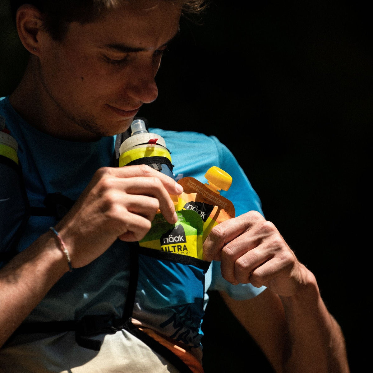 Person eating a naak ultra energy puree apple maple syrup against a dark background