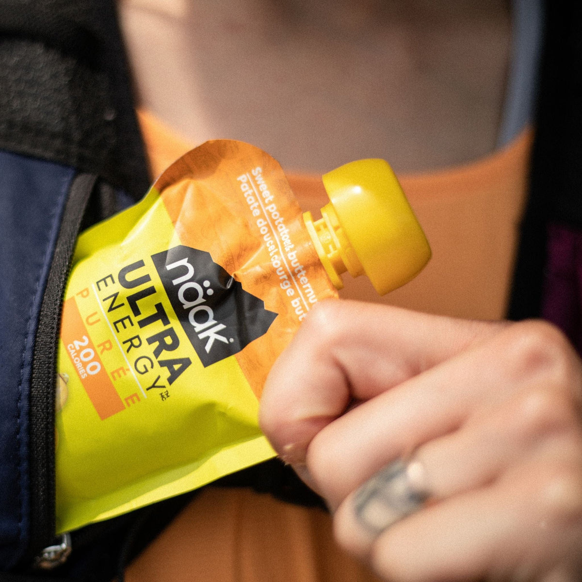 trail runner holding a naak ultra energy puree sweet potatoe butternut squash pouch
