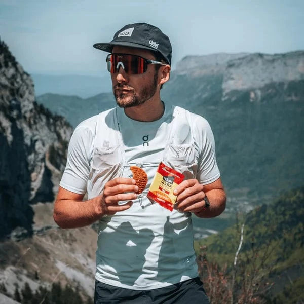 Man holding a naak ultra energy waffle in front of mountainous landscape